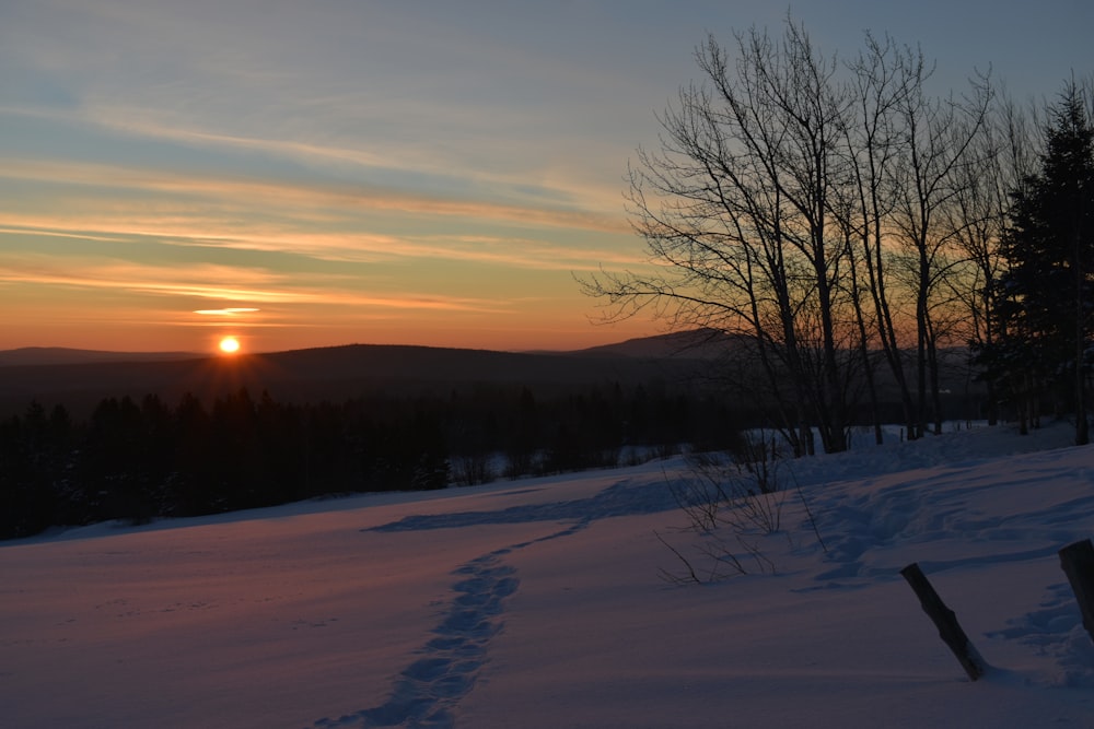 o sol está se pondo sobre uma colina nevada