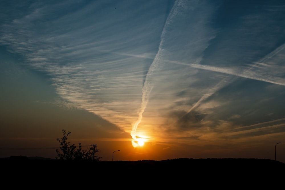 a sunset with contrails in the sky