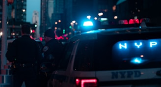 two nypd officers standing next to a police car