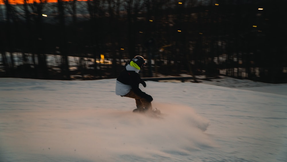 a person riding a snowboard down a snow covered slope