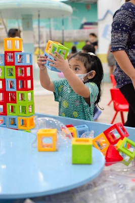 a little girl playing with blocks at a table