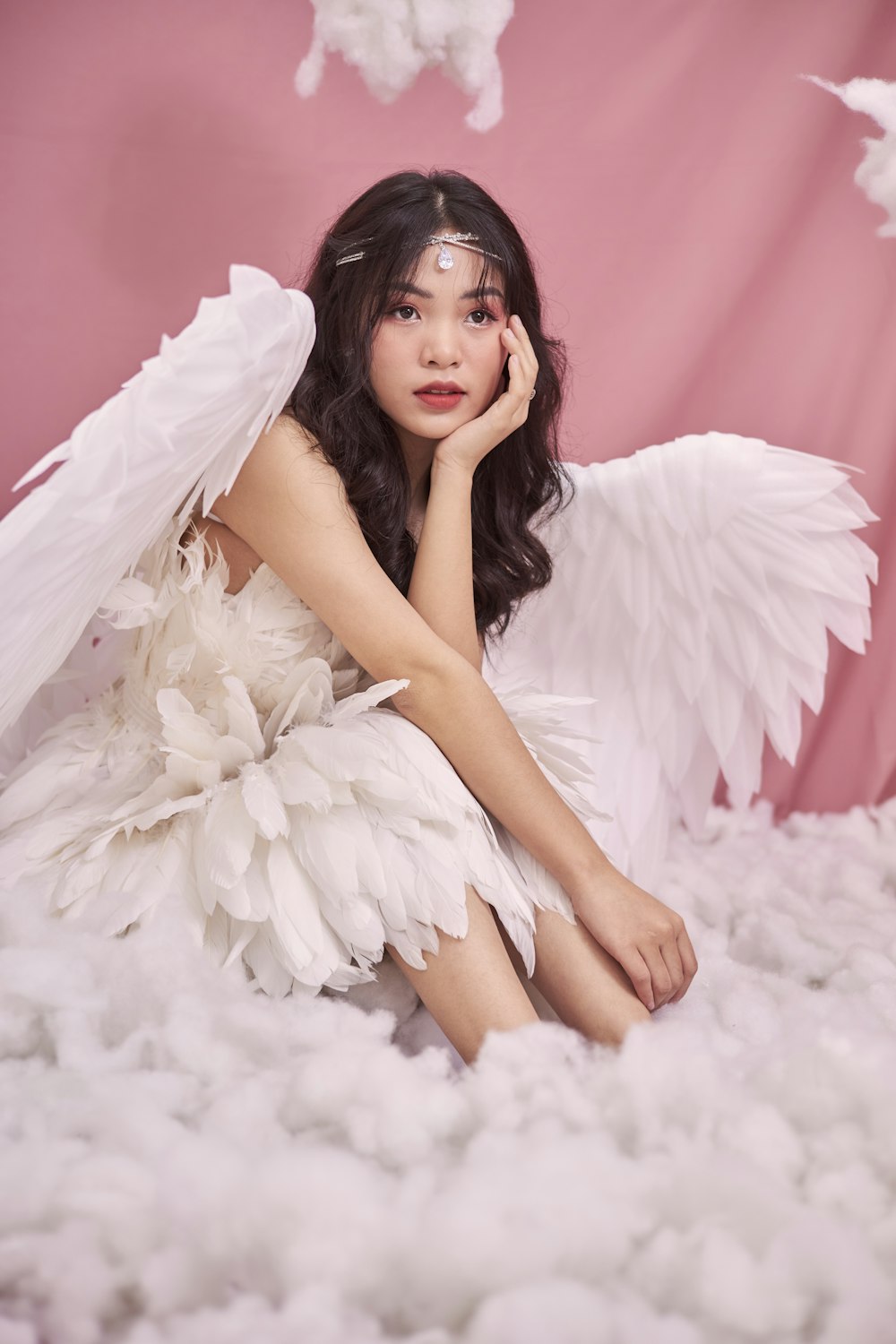 a woman sitting on top of a pile of white feathers