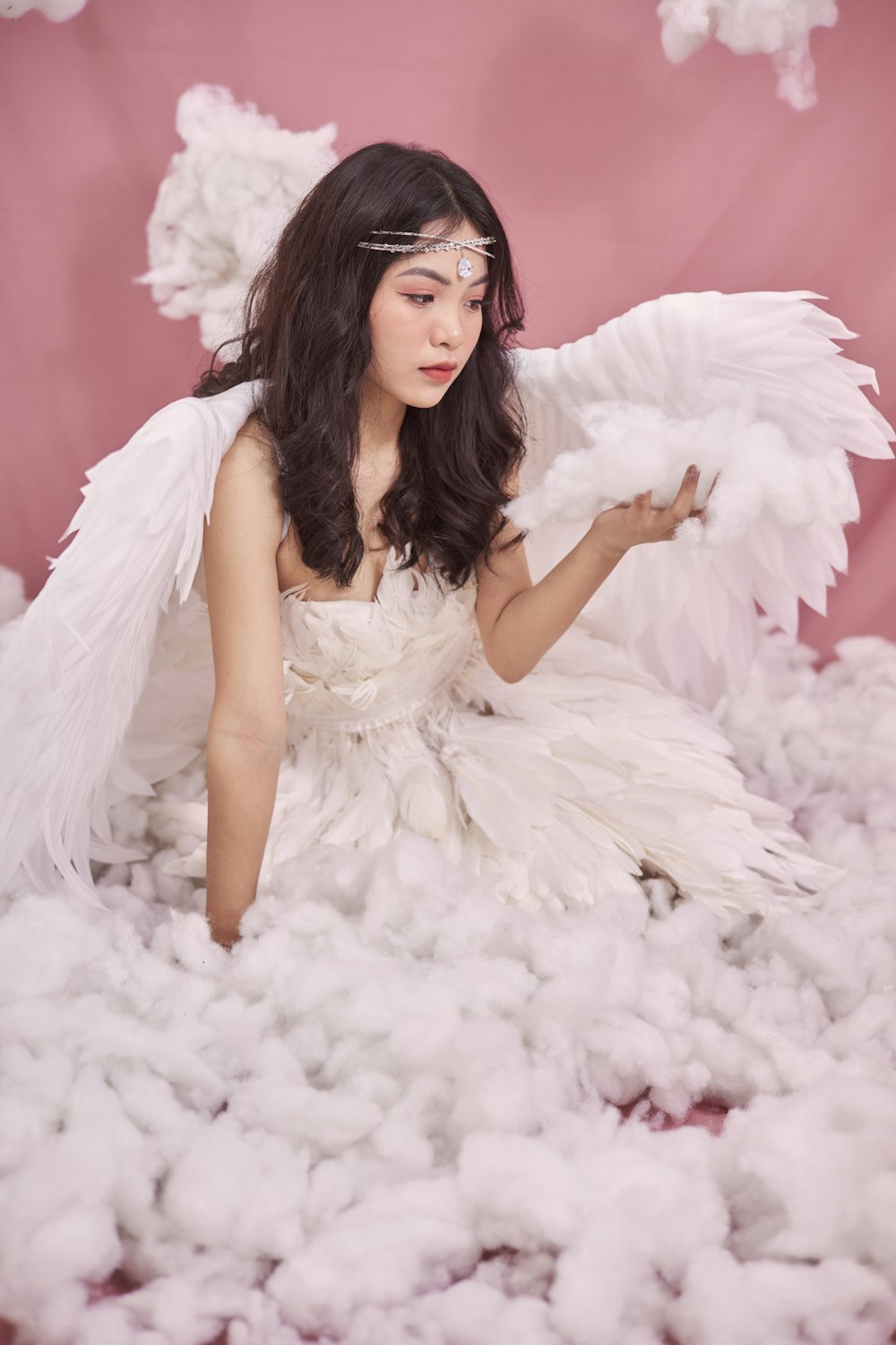a woman in a white dress sitting on a pile of cotton