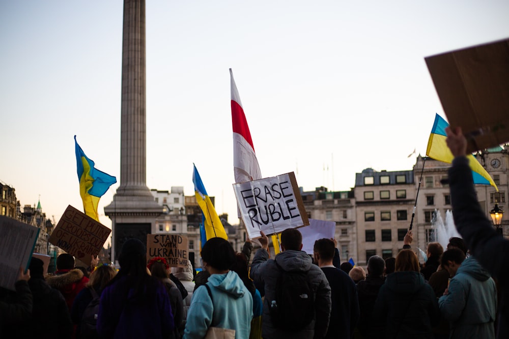 un gruppo di persone che reggono cartelli davanti a un monumento