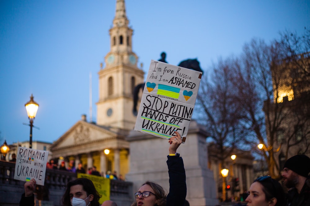 a group of people holding signs in front of a building