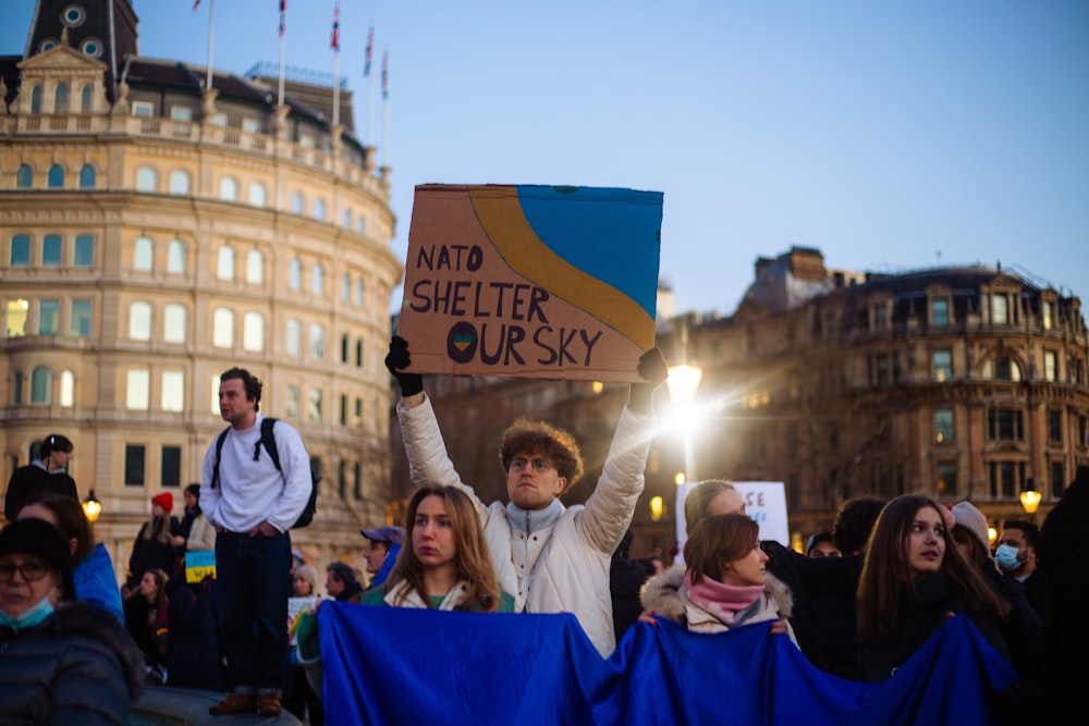 a man holding a sign in the middle of a crowd