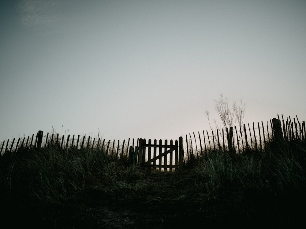 a wooden fence sitting on top of a grass covered hillside