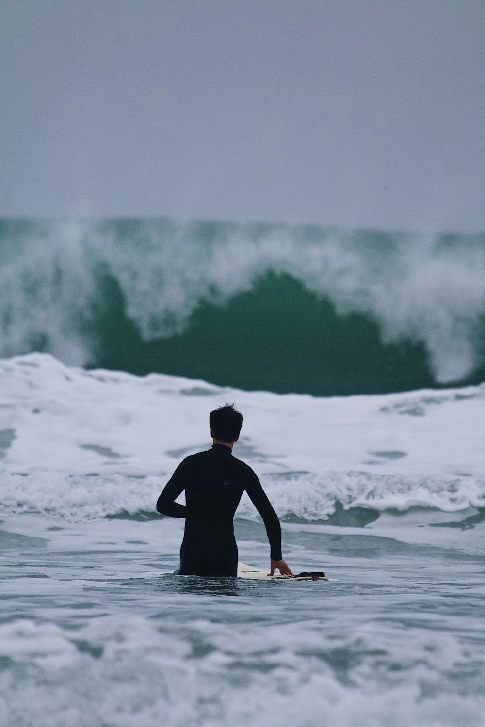 a man standing in the ocean with a surfboard