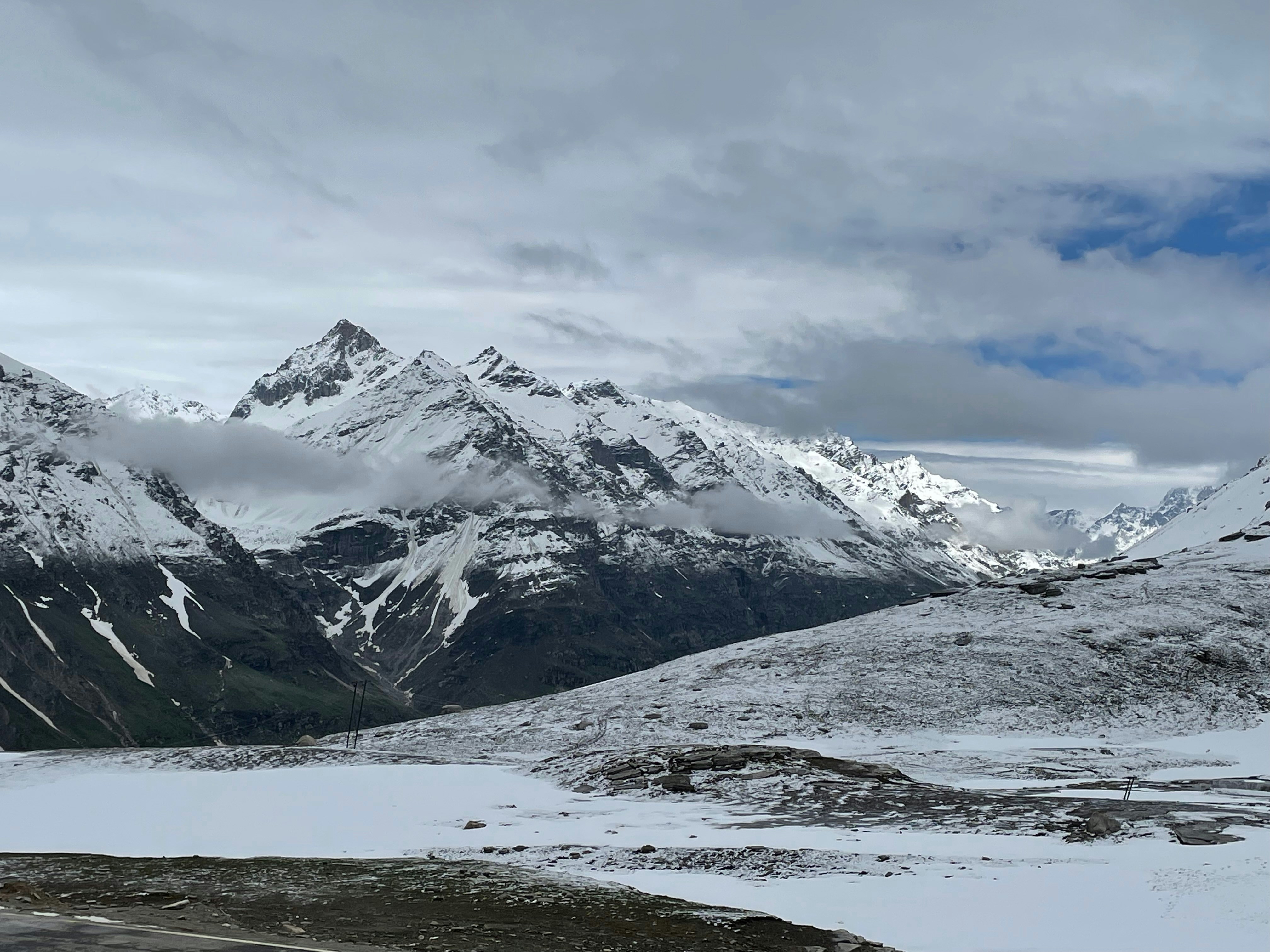 a mountain range covered in snow under a cloudy sky