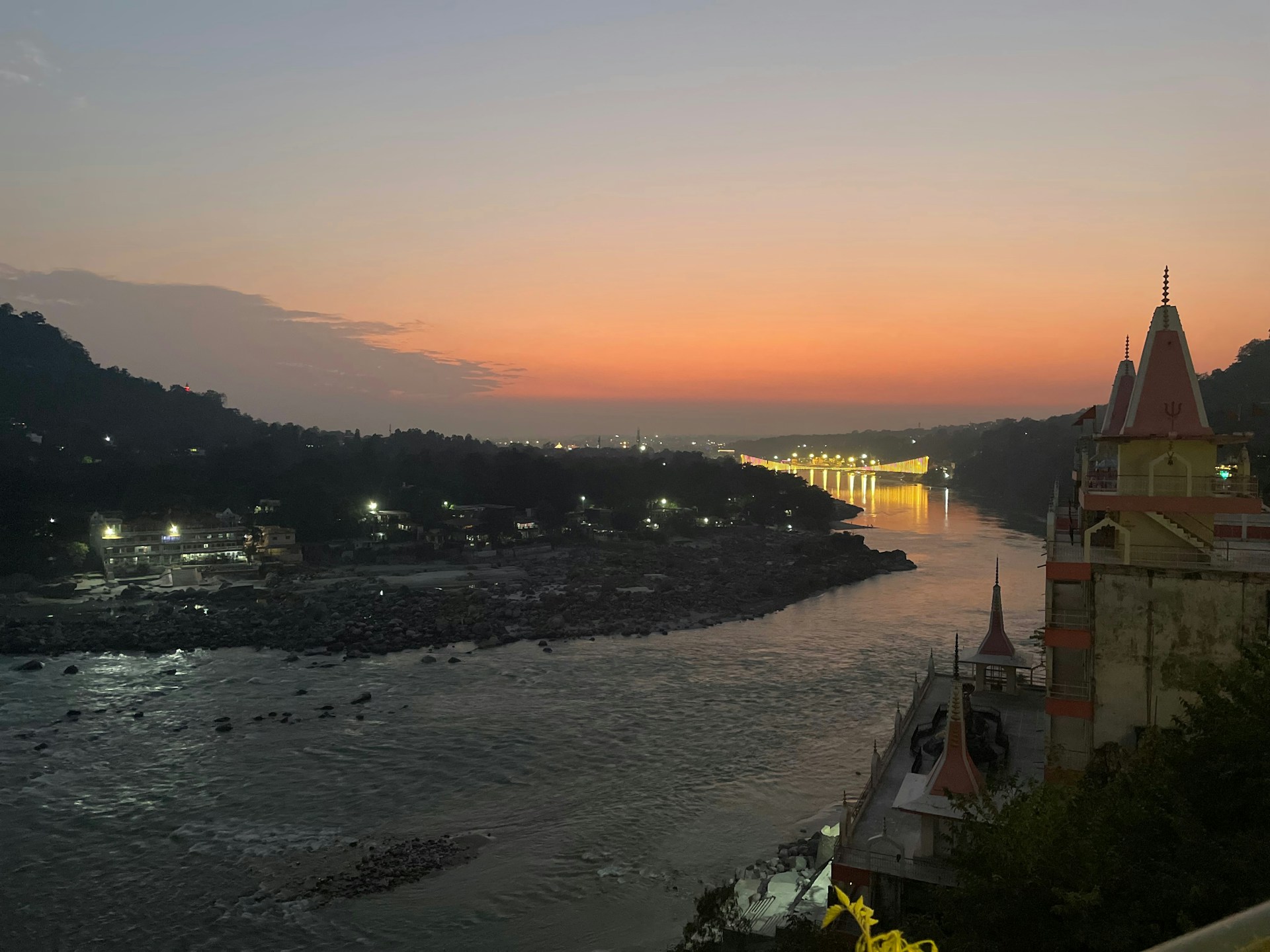 a sunset view of a river with a bridge in the background