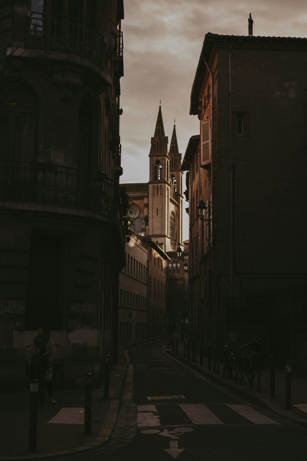 a narrow city street with a clock tower in the distance