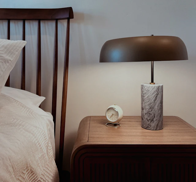 A bedroom with a bed, nightstand, and lamp