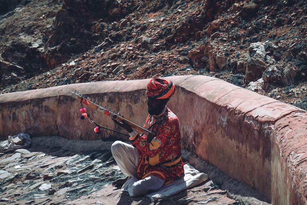 a man sitting on the ground playing a musical instrument