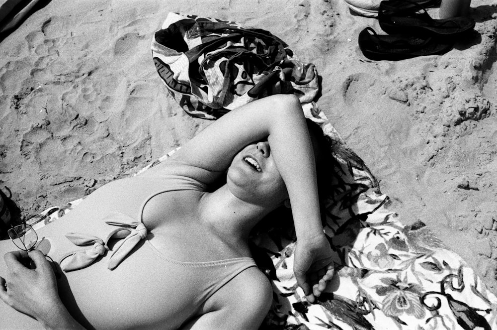 a woman laying on a towel on the beach