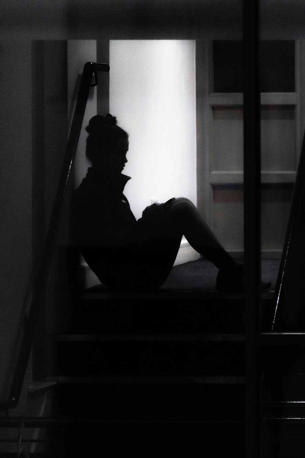 a silhouette of a person sitting on a set of stairs