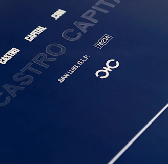 A close-up of a sleek dark blue cover design featuring text in white and light gray, including 'CASTRO CAPITAL .COM', 'SAN LUIS, S.L.P.', and a number '78214'. The design includes a stylized logo with interlocking letters.