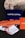 Several business cards are displayed in various colors and patterns. A dark blue card with white text reading 'Castro Capital' is prominently positioned in the background. In the foreground, there are numerous cards with woven red and orange designs, along with others featuring architectural imagery. Behind the blue card, a textured rock provides a contrasting natural element against the smooth cards.