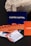 Several business cards are displayed in various colors and patterns. A dark blue card with white text reading 'Castro Capital' is prominently positioned in the background. In the foreground, there are numerous cards with woven red and orange designs, along with others featuring architectural imagery. Behind the blue card, a textured rock provides a contrasting natural element against the smooth cards.