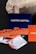 Several business cards are displayed in various colors and patterns. A dark blue card with white text reading 'Castro Capital' is prominently positioned in the background. In the foreground, there are numerous cards with woven red and orange designs, along with others featuring architectural imagery. Behind the blue card, a textured rock provides a contrasting natural element against the smooth cards.