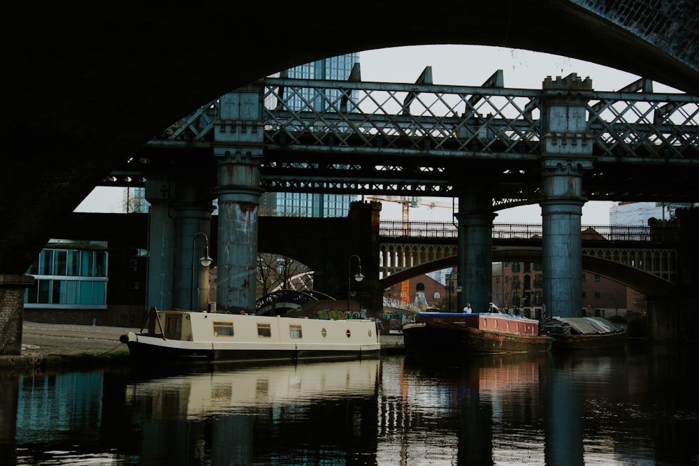 a boat floating under a bridge next to a river