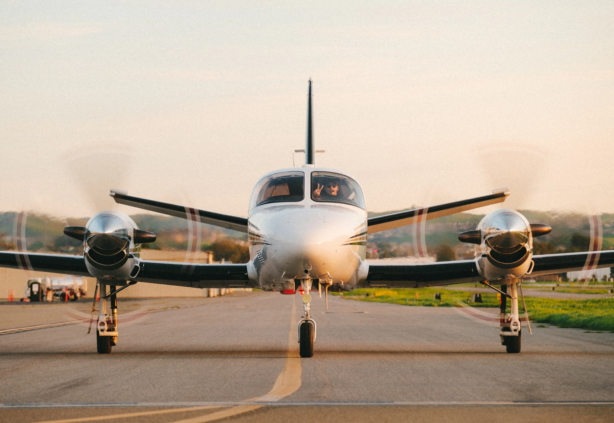 A twin-engine turboprop facing the camera on the runway at sunset, the aircraft behind the lowest turboprop charter cost