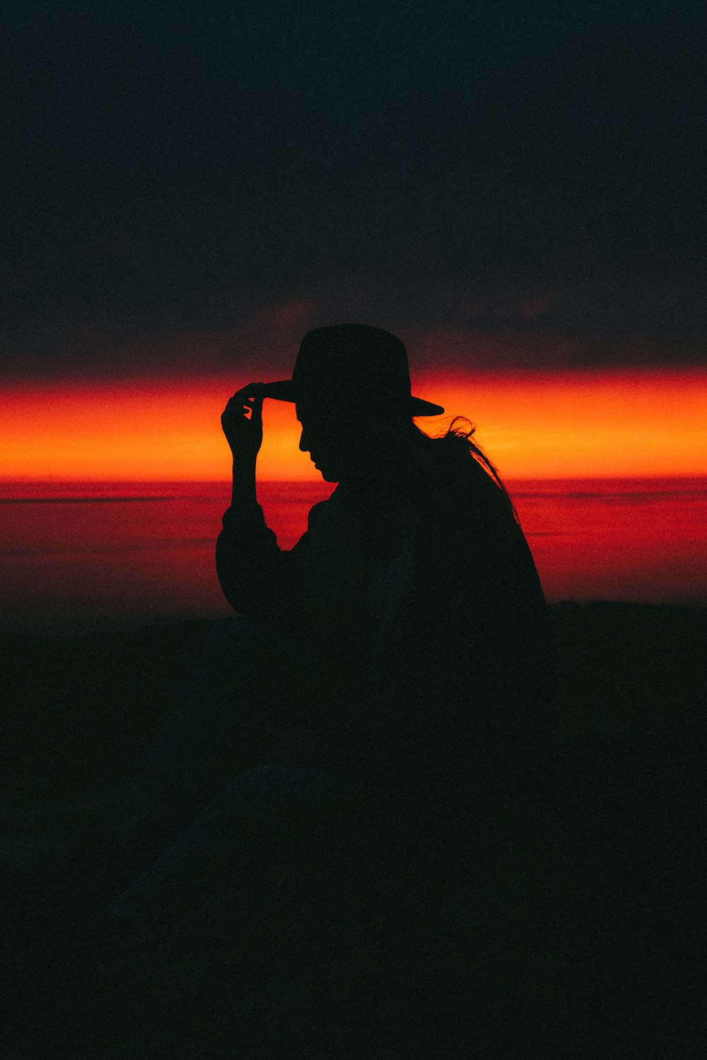 a person sitting on a hill with a sunset in the background