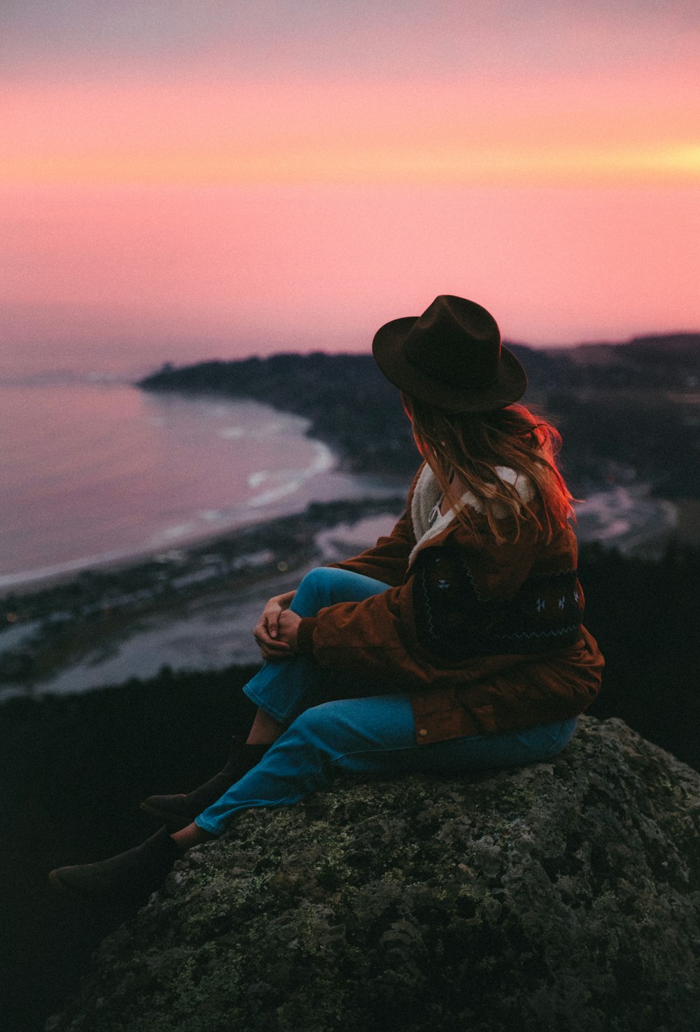 Eine Frau sitzt auf einem Felsen am Meer