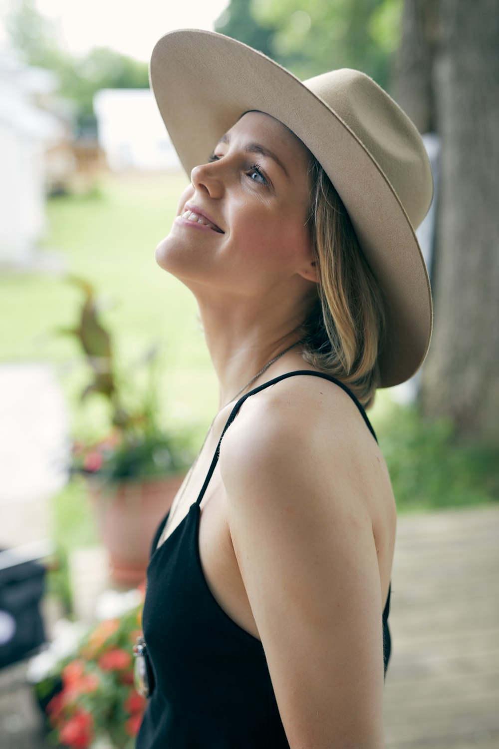 a woman wearing a hat standing in front of a tree