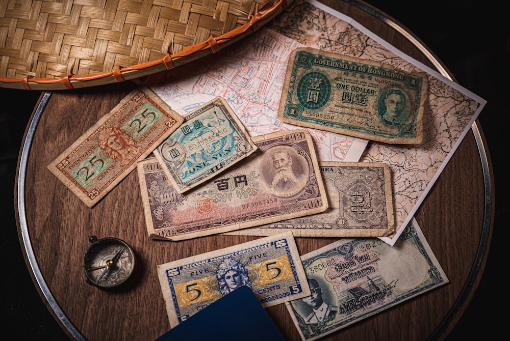 a wooden table topped with lots of different types of money