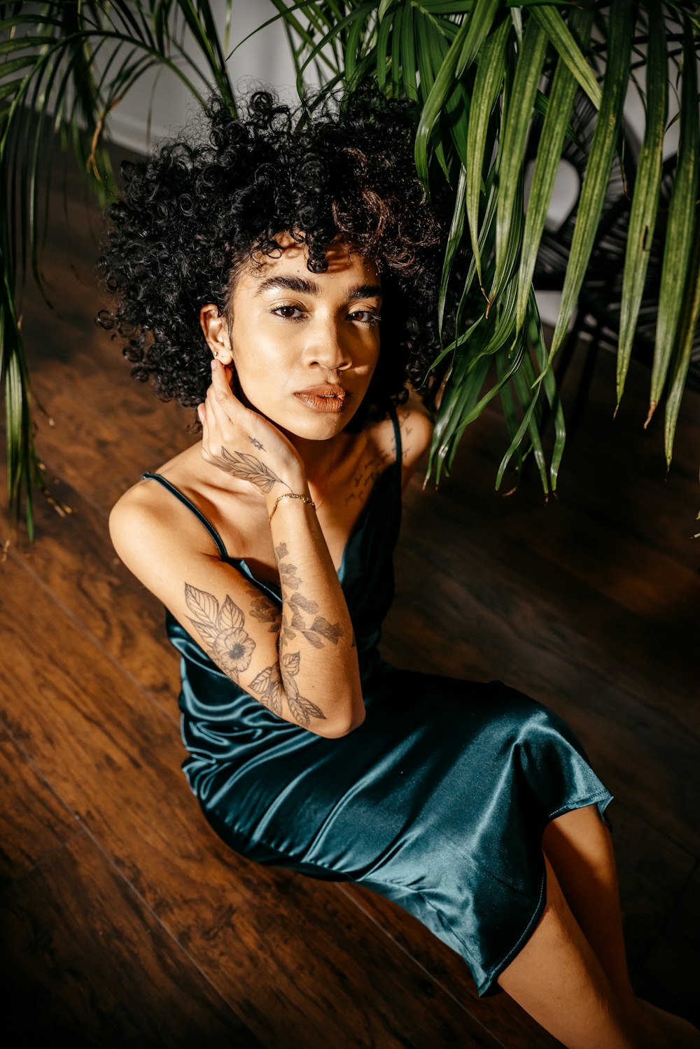 a woman sitting on the floor next to a plant