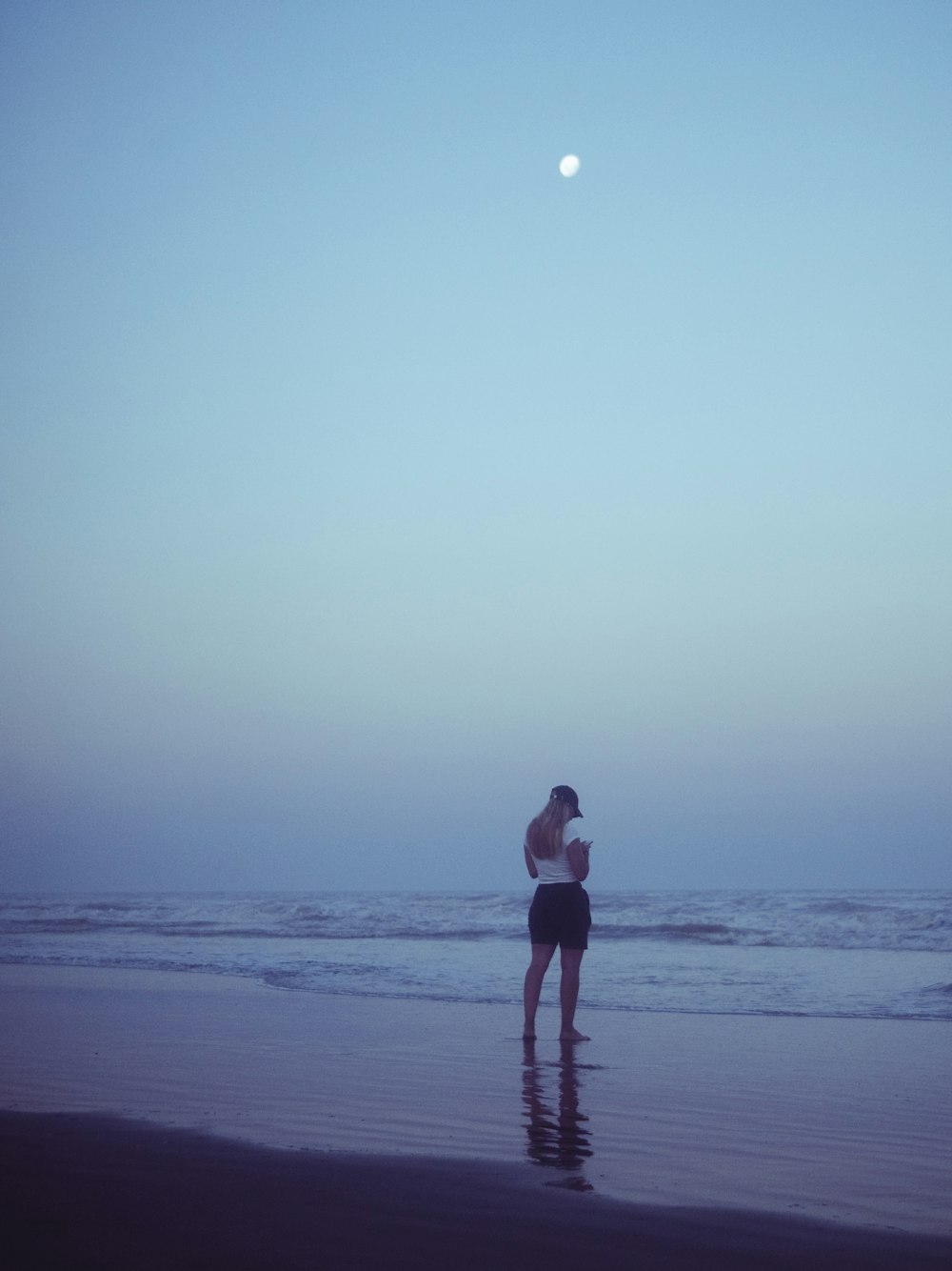 Una mujer parada en una playa junto al océano