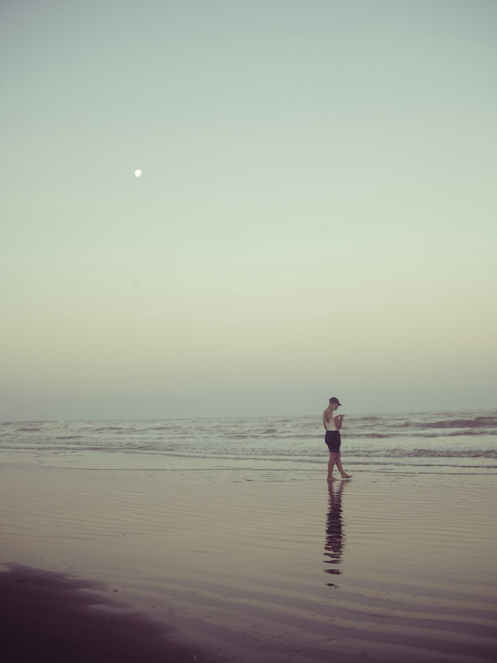 a woman standing on top of a beach next to the ocean