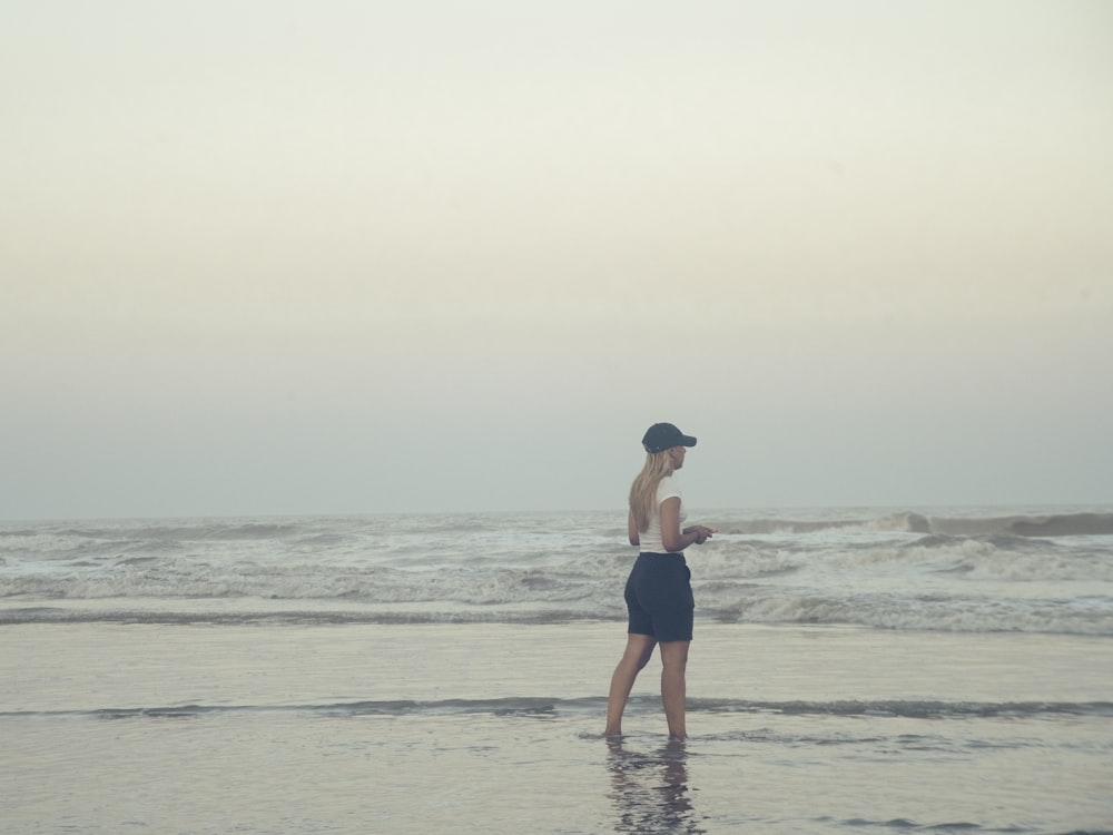 a woman standing on a beach next to the ocean