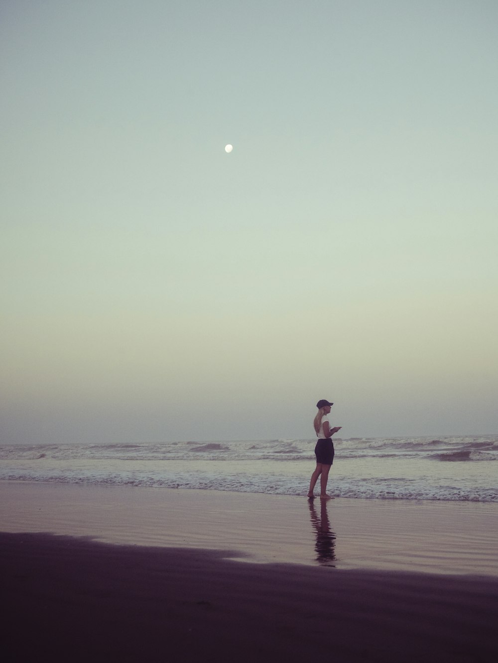 a woman standing on a beach next to the ocean