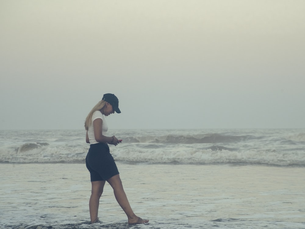 uma mulher que caminha em uma praia ao lado do oceano