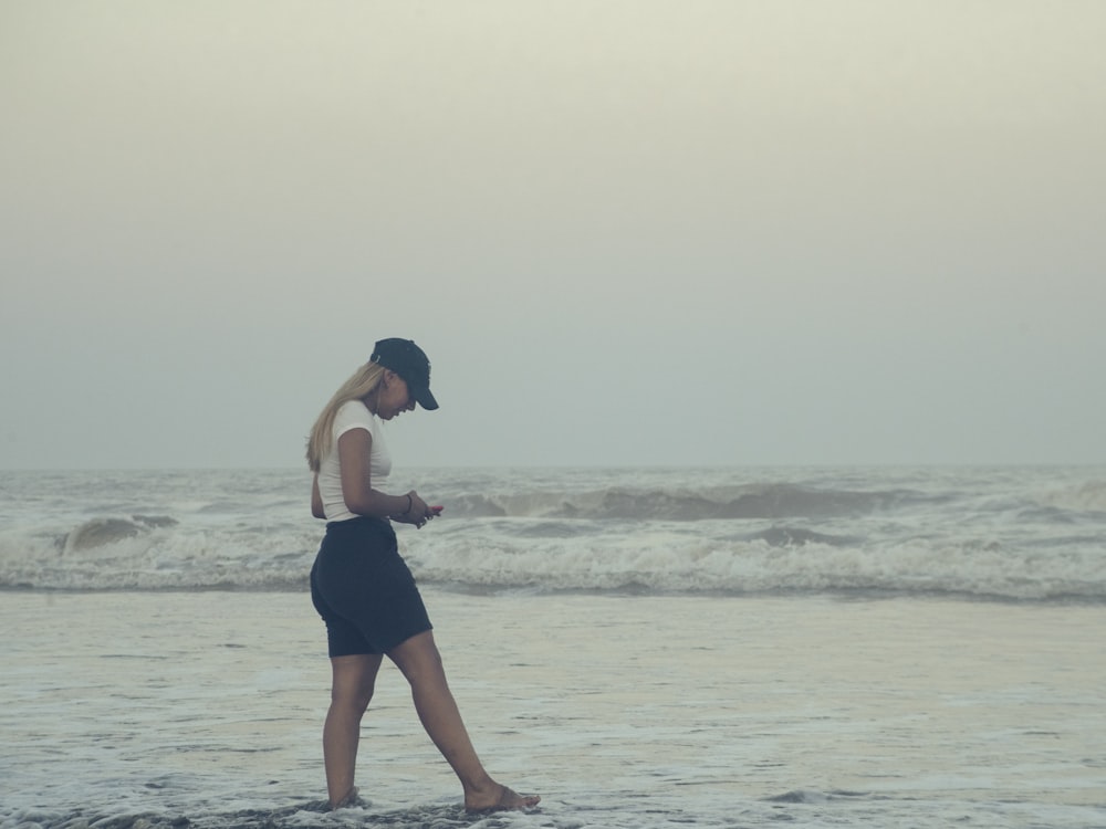 a woman walking on a beach next to the ocean