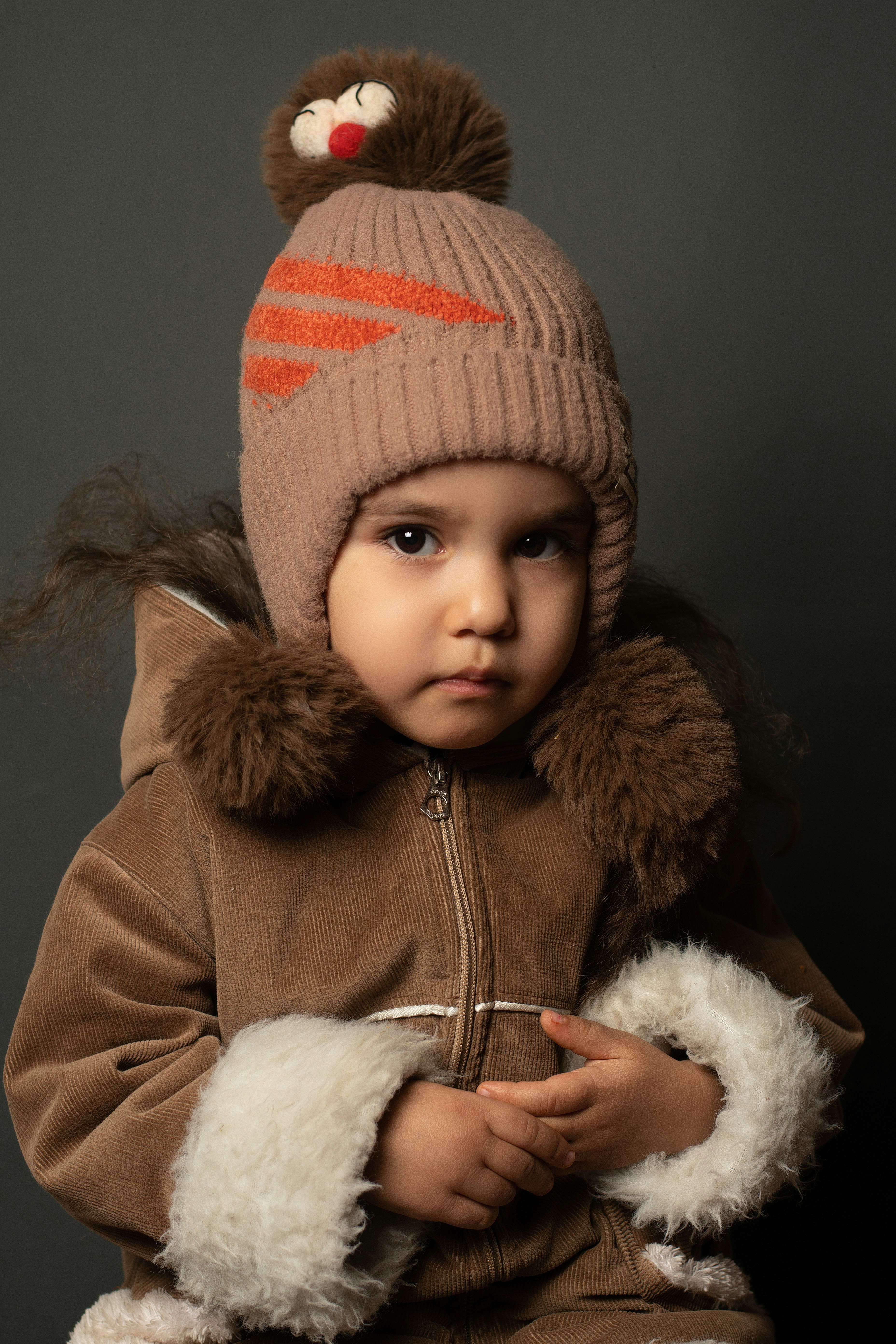 un petit enfant portant une veste marron et un chapeau marron