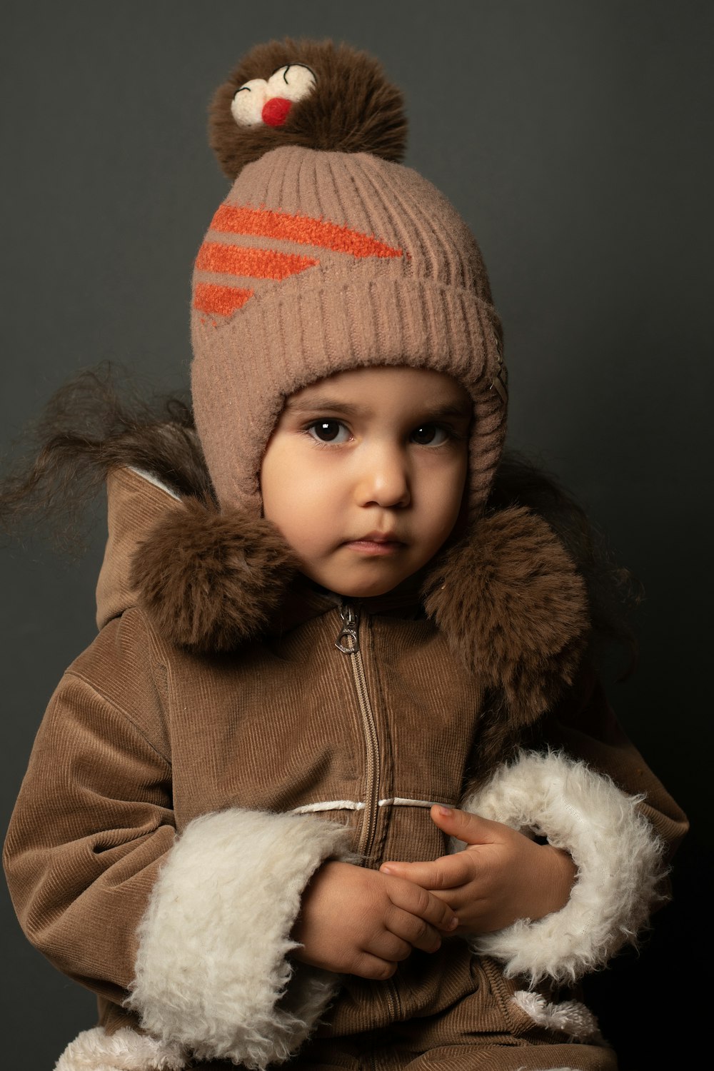 a small child wearing a brown jacket and a brown hat
