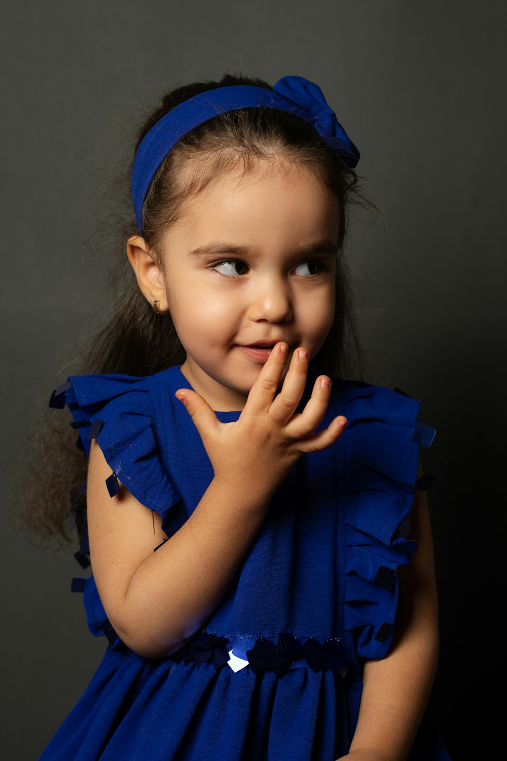 a little girl in a blue dress posing for a picture