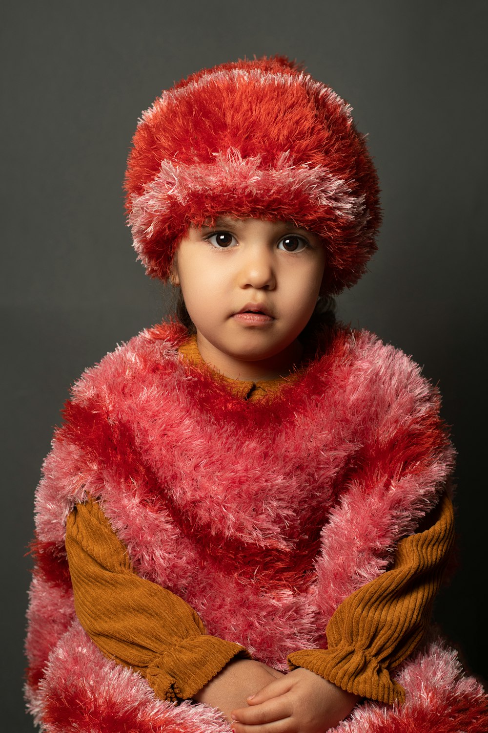 a young child wearing a red fur coat