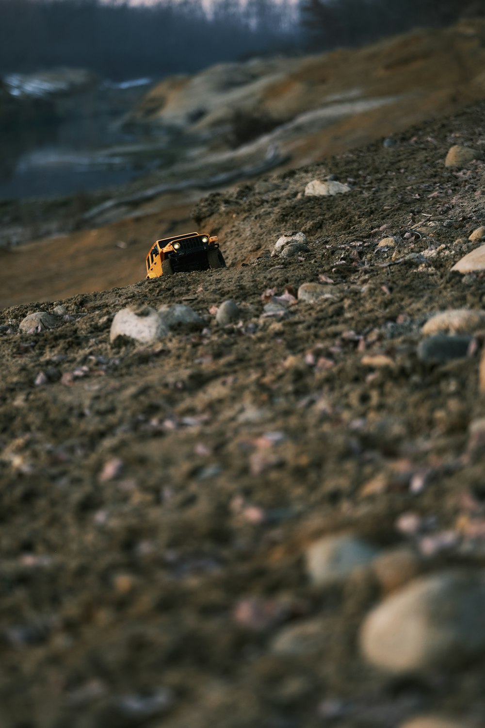 a yellow toy car sitting on top of a rocky hill