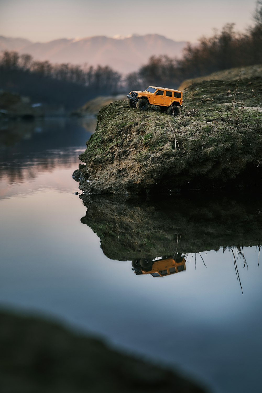 a yellow truck is parked on a hill by a body of water