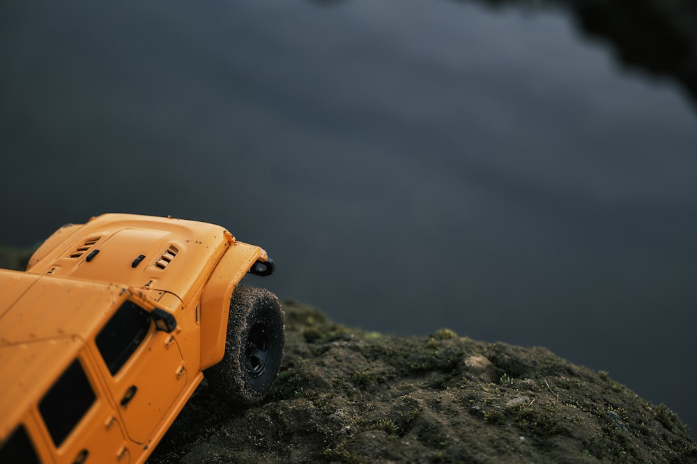 a yellow toy truck sitting on top of a rock