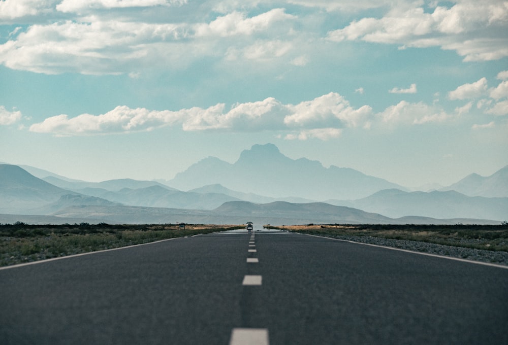 an empty road with mountains in the background