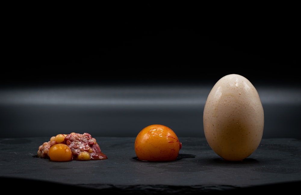 an egg sitting next to an orange on a table