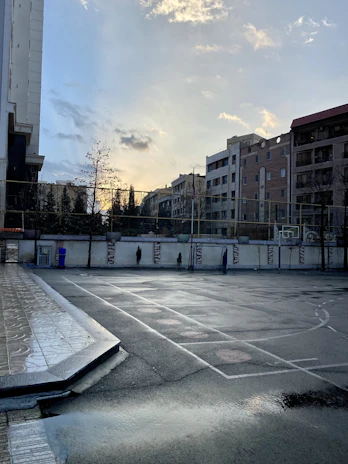 Wide-angle view of an empty futsal court at dawn, the city skyline softly glowing behind.