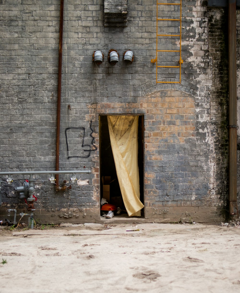 a brick building with a yellow curtain in the doorway