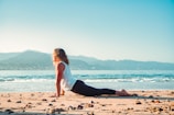 a woman is sitting on the beach doing yoga