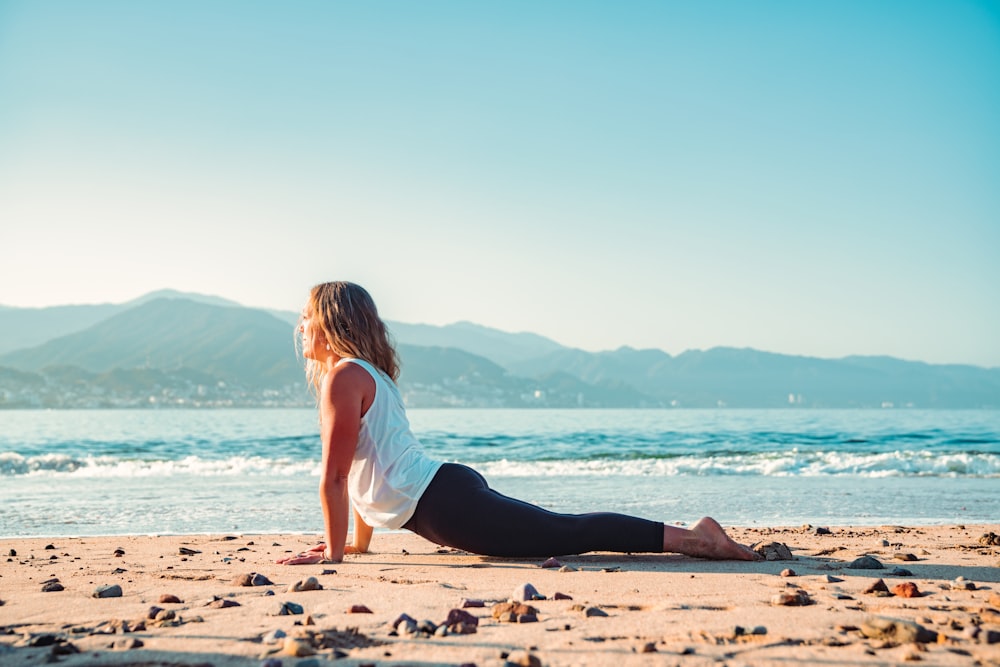 a woman is sitting on the beach doing yoga