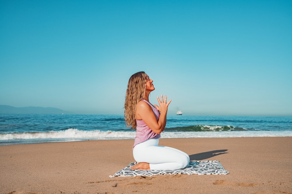 a woman sitting on top of a towel on top of a beach